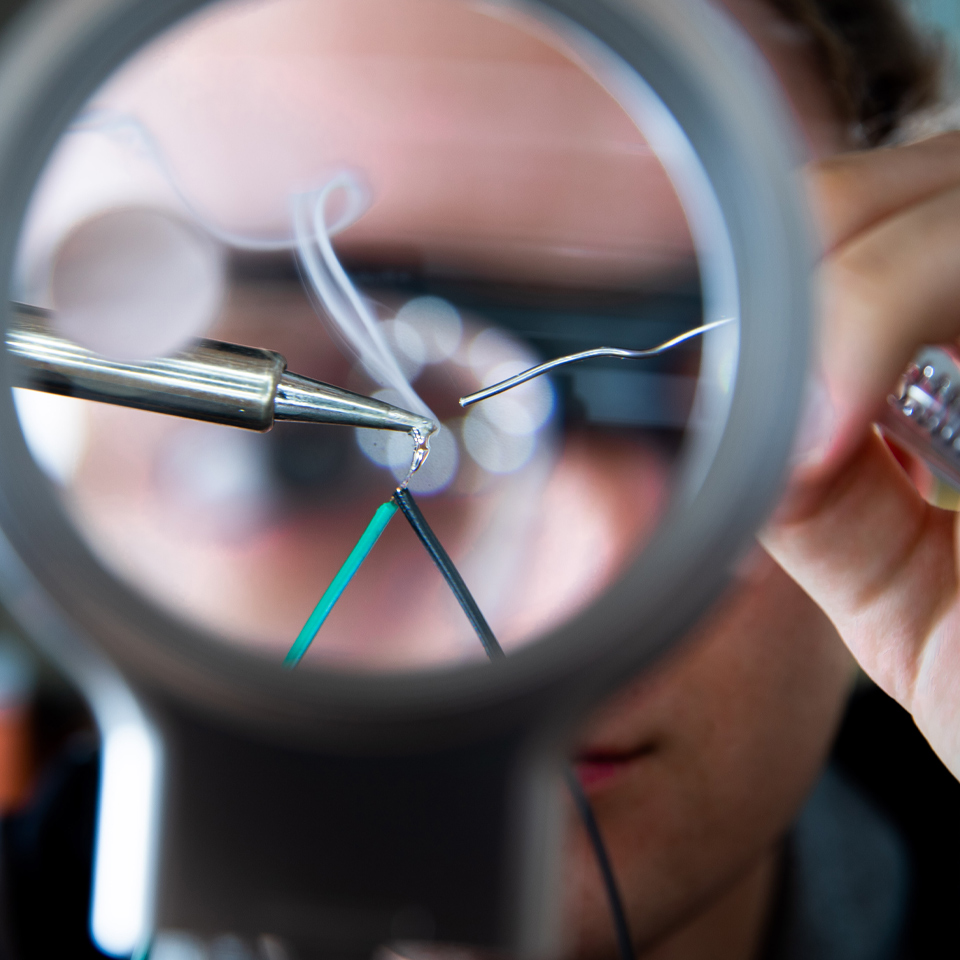 person using magnifying glass to solder